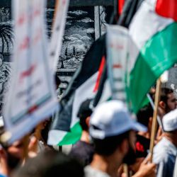Los manifestantes marchan con banderas palestinas frente a un mural que representa a los refugiados palestinos a lo largo de la pared de un edificio de la ONU durante una manifestación en la ciudad de Gaza, contra el acuerdo de los Emiratos Árabes Unidos con Israel para normalizar las relaciones. | Foto:MOHAMMED ABED / AFP