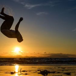 Un hombre realiza un salto mortal en una playa al atardecer en Banda Aceh. | Foto:Chaideer Mahyuddin / AFP