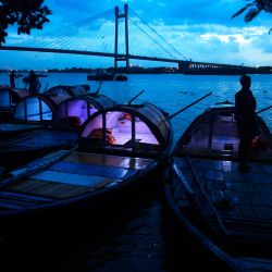 Los barqueros esperan con su barco de campo para llevar a la gente a dar un paseo por el río Ganges en Calcuta. | Foto:Dibyangshu Sarkar / AFP