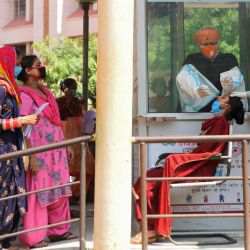 Los funcionarios de salud recogen una muestra de hisopo nasal de una mujer para realizar la prueba del coronavirus COVID-19, mientras la gente espera su turno en un hospital civil en Amritsar. | Foto:NARINDER NANU / AFP