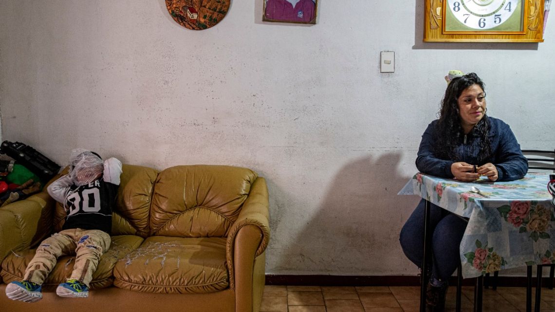 Denisse Leal sits next to her son Tomas at their home Santiago, Chile, Monday, Aug. 24, 2020. The family used to work as merchants in fairs all around Chile but the new coronavirus pandemic has left them with no way to earn a living, so now they disinfect subway cars in exchange for a tip.
