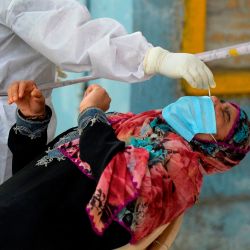 Un trabajador de la salud que usa equipo de protección personal recolecta una muestra de hisopo de una mujer en un centro gratuito de pruebas de coronavirus COVID-19 en Hyderabad. | Foto:NOAH SEELAM / AFP