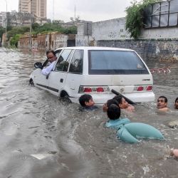 Los jóvenes nadan en la carretera Chundrigar, inundada, ubicada en el distrito comercial central de Karachi, después de que las fuertes lluvias monzónicas provocaron inundaciones. | Foto:Asif Hassan / AFP