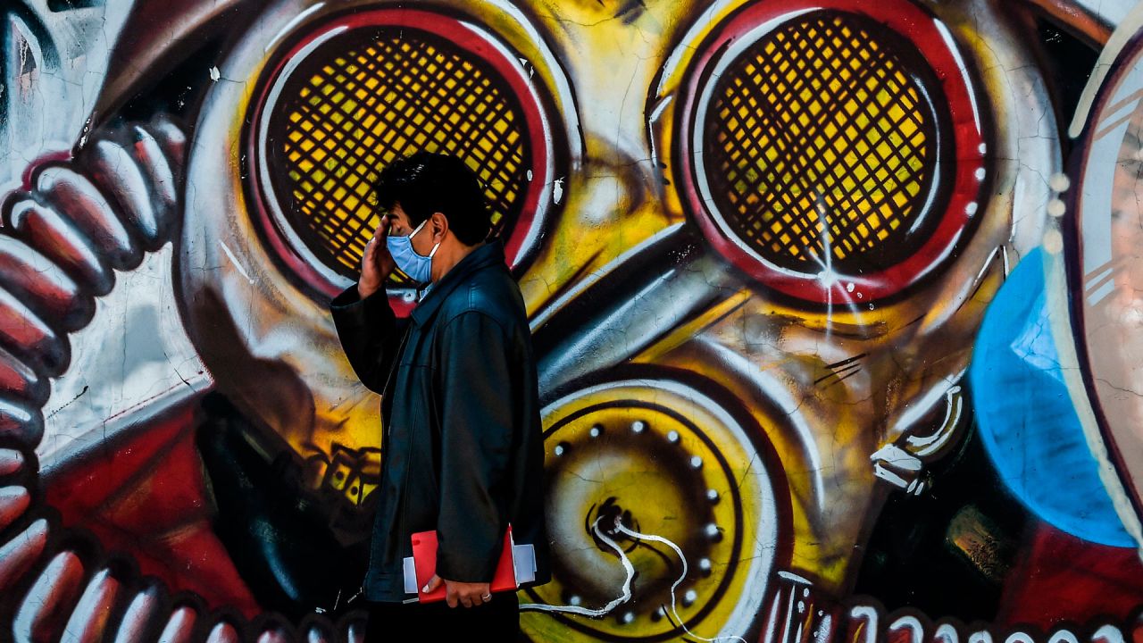Un hombre con mascarilla como medida preventiva contra el nuevo coronavirus COVID-19, camina junto a un grafiti en Bogotá. | Foto:Juan Barreto / AFP