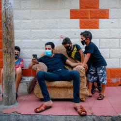 Un hombre palestino y niños con máscaras faciales debido a la pandemia del coronavirus se sientan afuera de un edificio en la ciudad de Gaza, durante un cierre en el enclave palestino debido al aumento de casos de infecciones por coronavirus. | Foto:MOHAMMED ABED / AFP