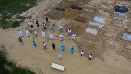 En esta fotografía aérea, familiares, voluntarios y trabajadores del cementerio ofrecen una oración frente al ataúd de una víctima del coronavirus COVID-19 durante un funeral en un cementerio en Nueva Delhi.