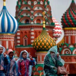 Personas con impermeables caminan por la Plaza Roja frente a la Catedral de San Basilio en un día lluvioso en Moscú. | Foto:Natalia Kolesnikova / AFP