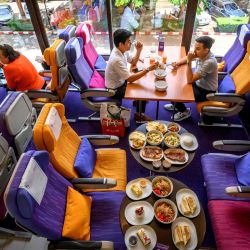 Las personas se sientan en los asientos del avión mientras cenan en un restaurante emergente con temática de aviones de Thai Airways en la sede de la aerolínea en Bangkok. | Foto:Mladen Antonov / AFP