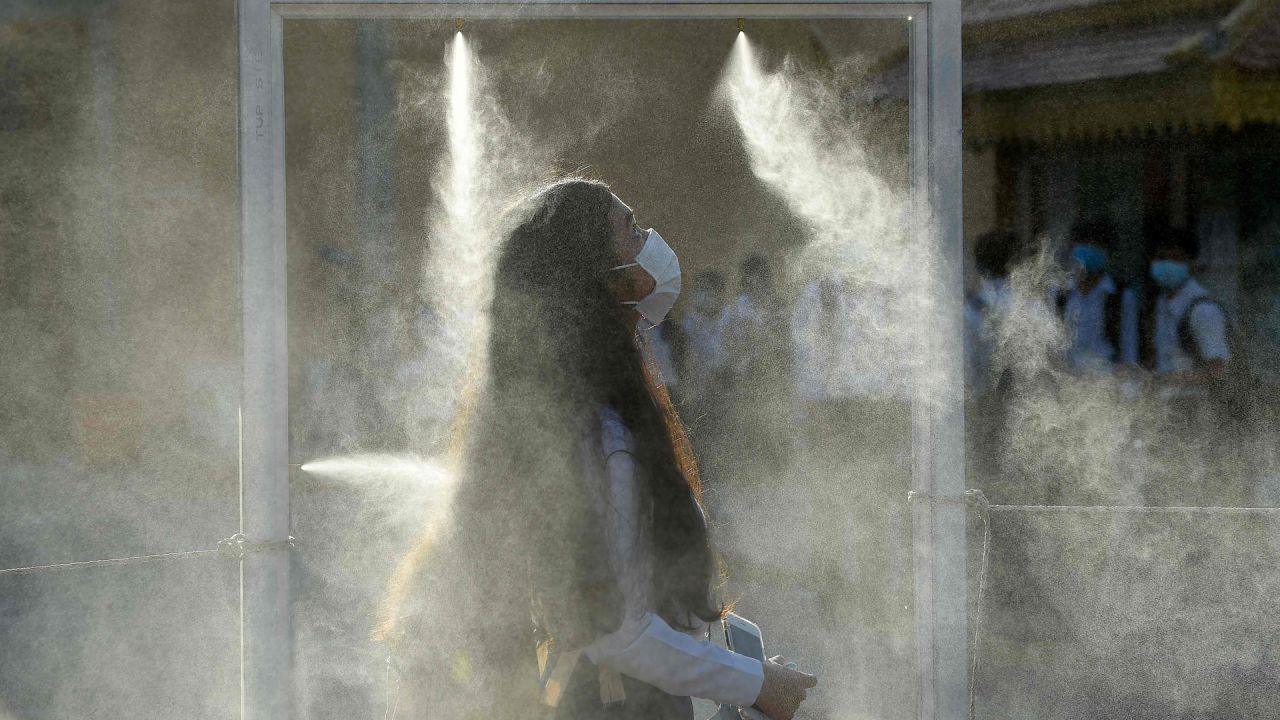 Un estudiante enfundado en una máscara facial atraviesa una puerta equipada con spray desinfectante como parte de las medidas contra el coronavirus COVID-19 en Phnom Penh cuando las escuelas reabren en todo el país. | Foto:TANG CHHIN Sothy / AFP