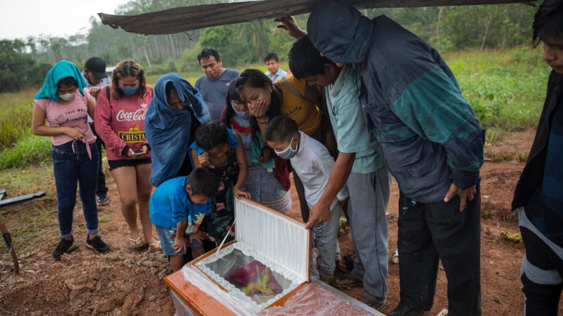Family members look in the coffin that contains the remains of Manuela Chavez who died from symptoms related to the new coronavirus at the age of 88, during a burial service in the Shipibo Indigenous community of Pucallpa, in Peru's Ucayali region, Monday, August 31, 2020.
