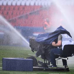 Un cameram se prepara para filmar mientras se sienta bajo dos chorros de riego para el césped antes del partido de fútbol francés L1 entre Paris Saint-Germain (PSG) y Metz, en el estadio Parc des Princes de París. | Foto:FRANCK FIFE / AFP