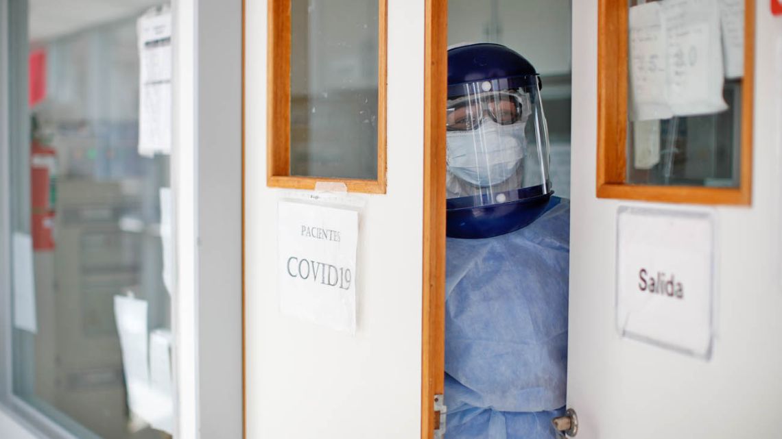 A doctor, dressed in full protective gear, looks out from an intensive care unit designated for COVID-19 patients.