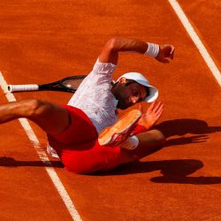 El serbio Novak Djokovic cae en la cancha mientras juega un punto contra el noruego Casper Ruud durante su partido de semifinales del Abierto de Italia masculino en el Foro Itálico en Roma. | Foto:Clive Brunskill / POOL / AFP