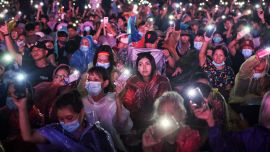 Manifestantes antigubernamentales sostienen sus teléfonos móviles en alto mientras participan en una manifestación a favor de la democracia en Bangkok.