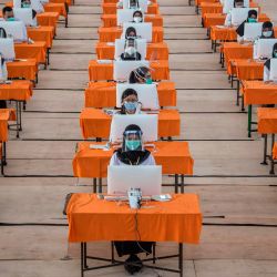 Los candidatos a empleados públicos estatales que usan máscaras y escudos como medida de precaución contra la propagación del coronavirus COVID-19 se someten a una prueba en Surabaya. | Foto: Juni Kriswanto / AFP