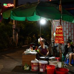 Una vendedora se sienta en su puesto de comida en la calle en Hanoi. | Foto:Manan Vatsyayana / AFP