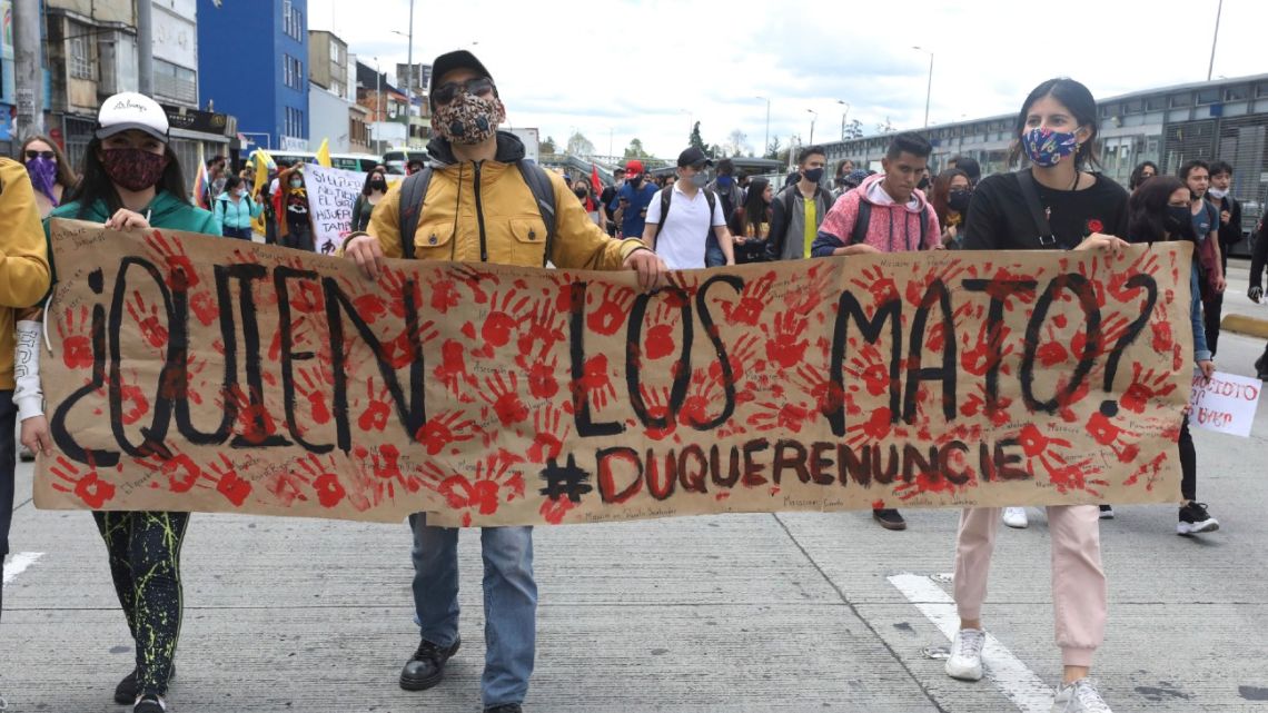University students march holding a poster with a message that reads in Spanish: "Who killed them?" during a demonstration against a wave of massacres, in Bogota, Colombia, Monday, September 21, 2020. 