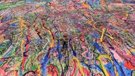 El artista británico contemporáneo Sacha Jafri se encuentra en su pintura récord titulada 'El viaje de la humanidad', en la ciudad emiratí de Dubai. - La pintura, que mide el tamaño de dos campos de fútbol, se puede ver en un hotel en Dubai, donde Jafri pasó meses encerrado debido a la pandemia de coronavirus.