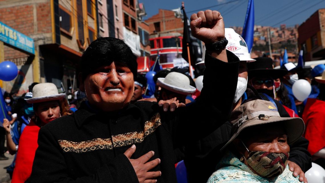 In this September 19, 2020, file photo, a supporter, wearing a mask depicting former president Evo Morales, strikes a pose during a campaign rally for Luis Arce Catacora, the Bolivian presidential candidate for the Movement Towards Socialism Party, or MAS, in La Paz, Bolivia. 