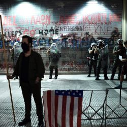 Un hombre se para cerca de agentes de la policía antidisturbios fuera del consulado de EE. UU., Durante una protesta contra la visita a Grecia del secretario de Estado de EE. UU. Mike Pompeo, en Salónica. | Foto:Sakis Mitrolidis / AFP