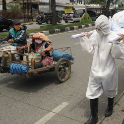 Un conductor de bicitaxi y su pasajero miran a los funcionarios locales que llevan un cadáver simulado para promover la conciencia sobre el coronavirus COVID-19 en Medan, en el norte de Sumatra. | Foto:MUHAMMAD ZULFAN DALIMUNTHE / AFP
