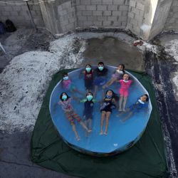 Territorios Palestinos, Ciudad de Gaza: Se ve a niños palestinos con máscaras faciales mientras se refrescan en una piscina portátil erigida en la azotea de un edificio residencial. | Foto:Mahmoud Ajjour / Zuma Wire / DPA