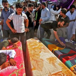 Los hombres iraquíes lloran por los ataúdes de miembros de una familia que murieron un día antes cuando un cohete alcanzó su casa cerca del aeropuerto de Bagdad, durante su funeral en la aldea de Al-Bu Shaban en el área de Radwaniyah en las afueras de la capital. | Foto:AHMAD AL-RUBAYE / AFP