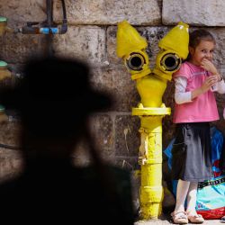 Niños judíos ultraortodoxos se paran junto a una boca de incendios pintada mientras pasa un hombre, antes de la celebración de Sucot, la Fiesta de los Tabernáculos, en el barrio ultraortodoxo de Mea Shearim en Jerusalén. | Foto:Emmanuel Dunand / AFP