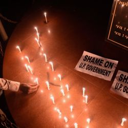Un miembro de la Unión Nacional de Estudiantes de la India coloca una vela junto a los carteles después de una vigilia con velas tras las acusaciones de que la policía india incineró por la fuerza el cuerpo de una víctima de 19 años, que supuestamente fue violada en grupo por cuatro hombres. en la aldea de Bool Garhi del estado de Uttar Pradesh, en Ahmedabad. | Foto:SAM PANTHAKY / AFP