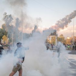 Chile, Santiago: un manifestante arroja un tanque de gas lacrimógeno durante los enfrentamientos con la policía luego de una protesta contra el gobierno en la Plaza Baquedano. | Foto:Pablo Rojas Madariaga / DPA