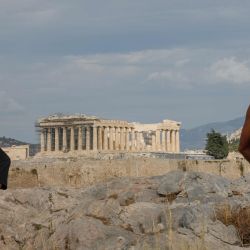 Los turistas se sientan bajo el sol en una colina con vistas a la antigua Acrópolis del siglo V a. C., en Atenas. - La industria del turismo en Grecia se ha visto muy afectada durante la pandemia del nuevo coronavirus Covid-19. | Foto:David Gannon / AFP