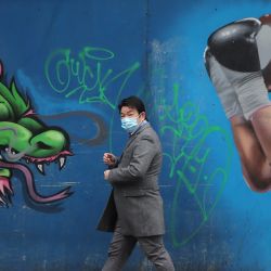  Irlanda, Dublín: un hombre usa una máscara facial mientras pasa junto a un dibujo de graffiti en la aldea de Drumcondra. | Foto:Niall Carson / PA Wire / DPA