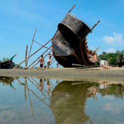 Los trabajadores reparan el casco de un barco de pesca en una playa en Cox's Bazar. | Foto:Munir Uz zaman / AFP