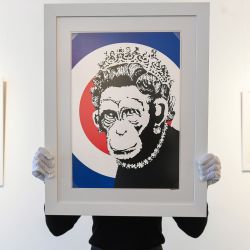 Inglaterra, Londres: la asistente de la galería Sophia Shim sostiene una impresión de edición limitada de Monkey Queen (2003) de Banksy. | Foto:Kirsty O'connor / PA Wire /DPA