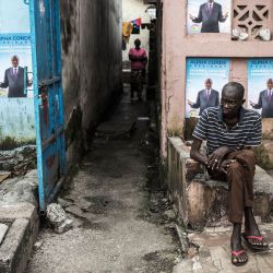 Un hombre se sienta frente a los carteles de campaña del presidente Alpha Conde en Conakry. - El presidente aspira a un tercer mandato con las elecciones presidenciales que se celebrarán el 18 de octubre de 2020, desafiando a los críticos que dicen que este año se vio obligado a aprobar una nueva constitución que le permitió eludir los límites presidenciales de dos mandatos. | Foto:JOHN WESSELS / AFP