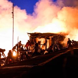 Los residentes de Kibera forman una cadena humana mientras pasan agua para extinguir un incendio que destruyó a los chabolas en el área de Maranatha del extenso barrio pobre que comenzó al anochecer en Nairobi. | Foto:Gordwin Odhiambo / AFP