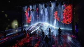 La gente visita una sala de cascada de instalación digital llena de flores que parece fluir sobre una roca, en la exposición TeamLab Borderless en el Museo de Arte Digital Mori Building en Tokio.