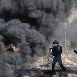 Las fuerzas de seguridad israelíes toman posiciones detrás de neumáticos en llamas durante los enfrentamientos con manifestantes palestinos en una manifestación semanal en la aldea de Kfar Qaddum en Cisjordania. | Foto:Jaafar Ashtiyeh / AFP