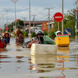 La gente camina a través de las inundaciones en las afueras de Phnom Penh. | Foto:Tang Chhin Sothy / AFP