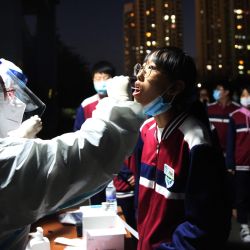 Esta foto muestra a un trabajador de la salud tomando un hisopo de un estudiante de secundaria para que le hagan la prueba del coronavirus COVID-19, como parte de un programa de pruebas masivas luego de un nuevo brote de coronavirus en Qingdao, en la provincia oriental de Shandong, en China. | Foto:STR / AFP