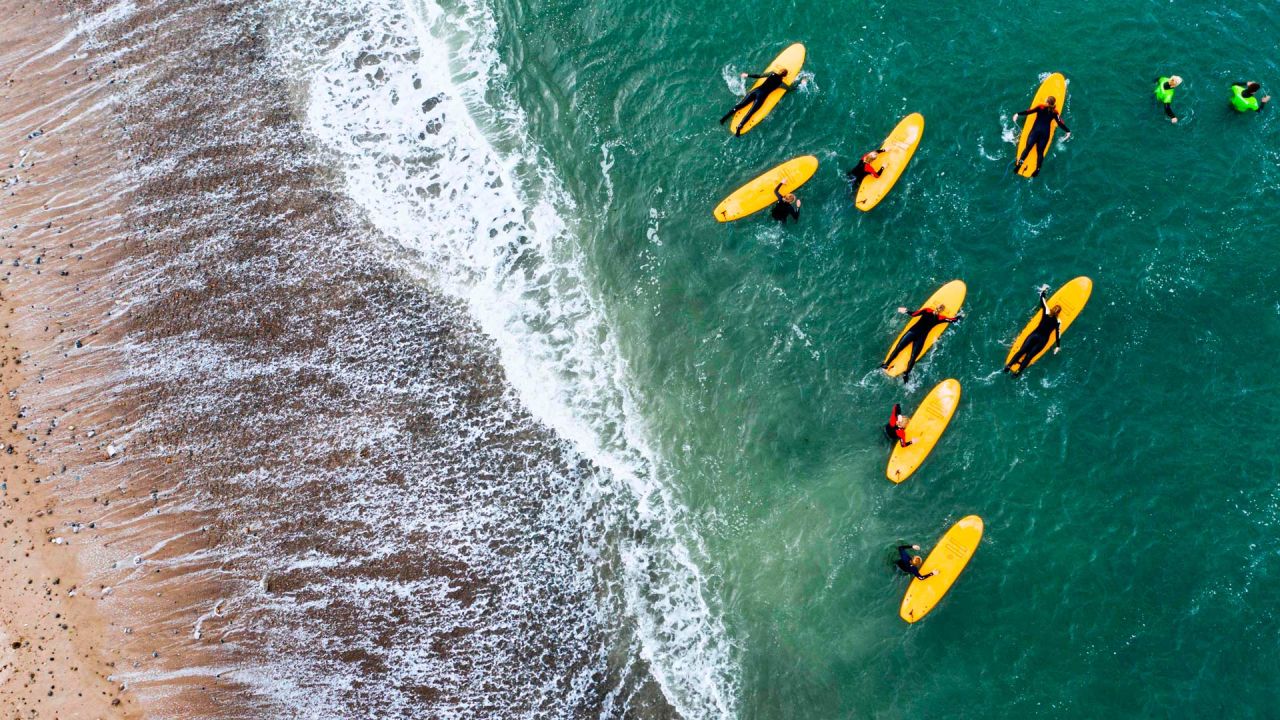 Esta imagen de vista aérea muestra a los surfistas de un campamento de surf local metiéndose en el agua para una sesión de surf en Klitmoller, Dinamarca. | Foto:Jonathan Nackstrand / AFP