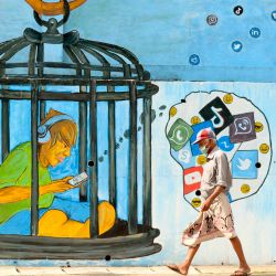 Un hombre que usa una mascarilla como medida preventiva contra el coronavirus Covid-19 pasa frente a un mural en Colombo. | Foto:LAKRUWAN WANNIARACHCHI / AFP