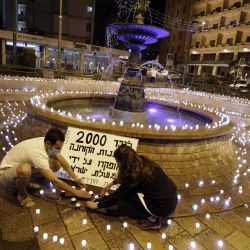 Activistas israelíes antigubernamentales colocan velas en honor a las víctimas de la pandemia de coronavirus y para protestar contra el gobierno, en el centro de Jerusalén. | Foto:MENAHEM KAHANA / AFP