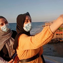 Mujeres palestinas se toman una selfie al atardecer en la ciudad de Gaza en medio de estrictas restricciones debido a la pandemia de COVID-19. | Foto:Mohammed Abed / AFP