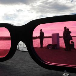 La gente de pie detrás de grandes lentes rosas observa el mar durante un día soleado. | Foto:Bernd Wüstneck / DPA