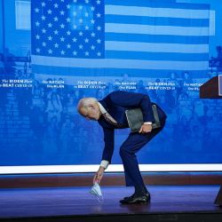 El candidato presidencial demócrata Joe Biden recoge su mascarilla protectora después de dejarla caer mientras abandonaba el escenario luego de sus comentarios para combatir la pandemia de coronavirus en el teatro The Queen el en Wilmington, Delaware. | Foto:Drew Angerer / Getty Images / AFP