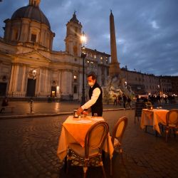 Un empleado limpia una mesa en una terraza vacía en la plaza Piazza Navona en Roma, antes de que entre en vigor un toque de queda por el virus nocturno en la región de Lazio como medida contra la propagación de la pandemia Covid-19. | Foto:Filippo Monteforte / AFP