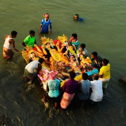 Los devotos hindúes se preparan para sumergir un ídolo de la diosa hindú Durga de diez manos en las aguas del río Ganges durante el festival Durga Puja, en Calcuta. | Foto:Dibyangshu Sarkar / AFP