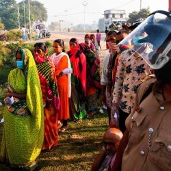 Un policía hace guardia mientras los votantes hacen cola para emitir sus votos para las elecciones de la asamblea estatal de Bihar en un colegio electoral en Patna. | Foto:Prakash Singh / AFP