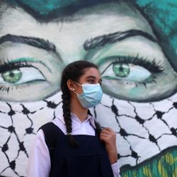 Territorios Palestinos, Gaza: una estudiante palestina se para frente a un graffiti camino a una escuela mientras las escuelas reabren gradualmente en medio del brote de coronavirus (COVID-19). | Foto:Mahmoud Ajjour / DPA